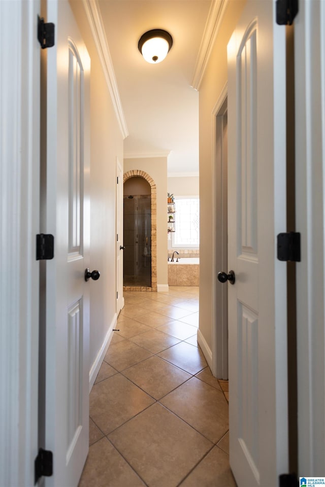 corridor with tile patterned flooring, crown molding, and baseboards