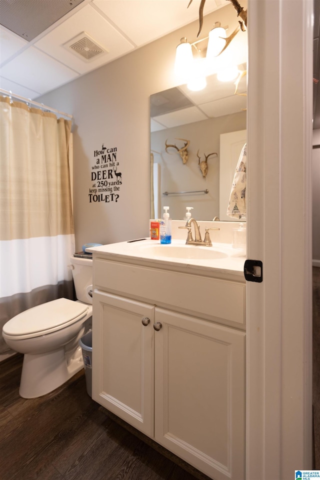 full bath with visible vents, toilet, wood finished floors, vanity, and a paneled ceiling