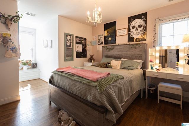 bedroom with baseboards, a notable chandelier, visible vents, and wood finished floors