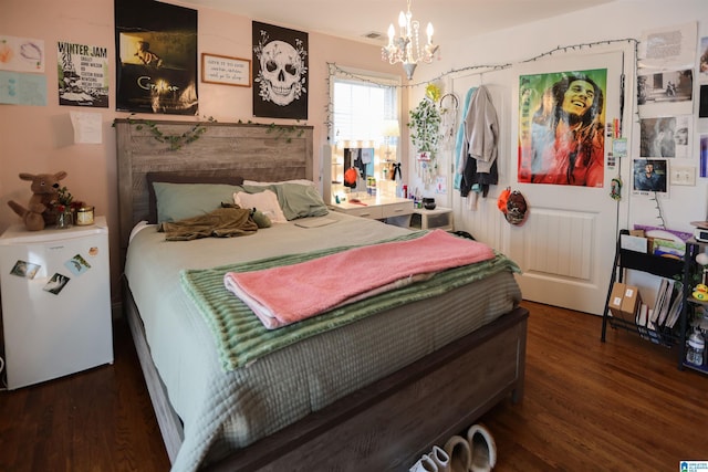 bedroom with wood finished floors, visible vents, and an inviting chandelier