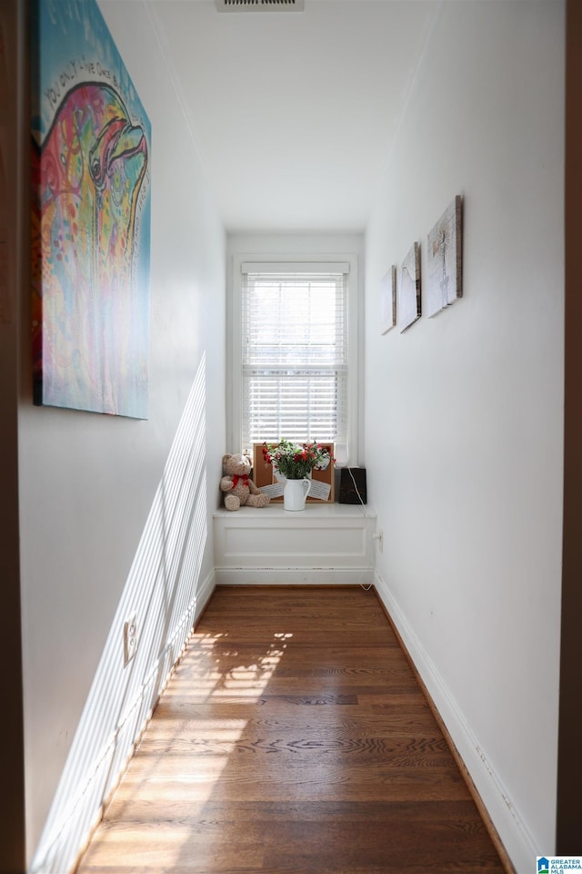 hall with visible vents, baseboards, and wood finished floors