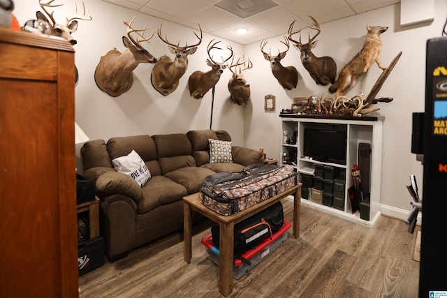 living area with a drop ceiling, wood finished floors, and baseboards