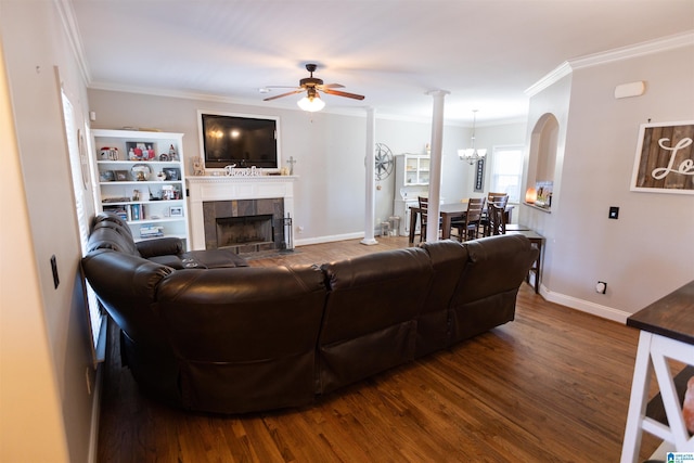 living area featuring baseboards, a tiled fireplace, ornamental molding, wood finished floors, and ceiling fan with notable chandelier