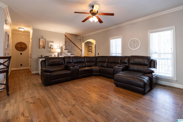 living area with arched walkways, wood finished floors, stairs, and a healthy amount of sunlight