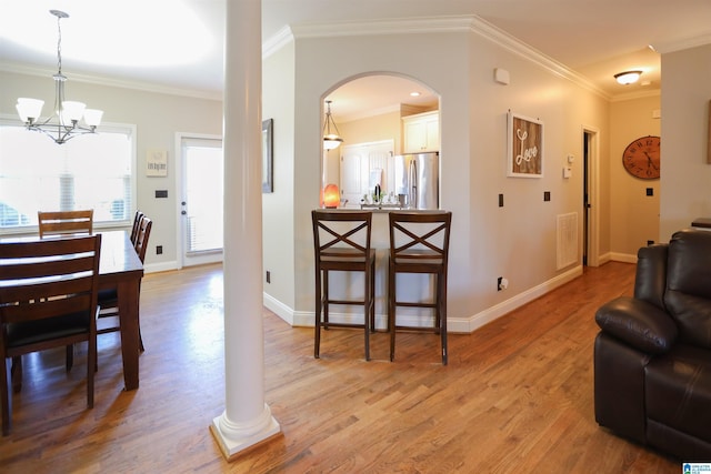 interior space with a notable chandelier, ornamental molding, light wood-style flooring, and baseboards