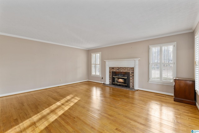 unfurnished living room with a brick fireplace, light wood-type flooring, plenty of natural light, and ornamental molding