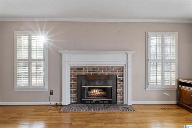 details with wood-type flooring, crown molding, and a brick fireplace