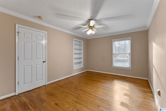 unfurnished room featuring light wood-type flooring, ceiling fan, crown molding, and built in features