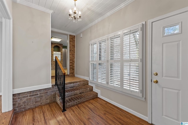 foyer entrance with a chandelier, wood-type flooring, crown molding, brick wall, and wood ceiling