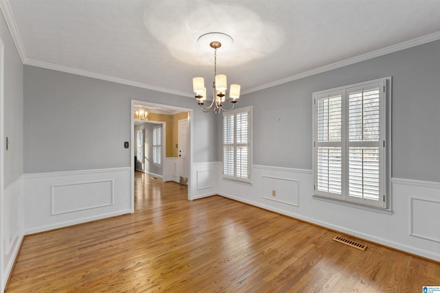 unfurnished dining area featuring a notable chandelier, ornamental molding, and hardwood / wood-style flooring