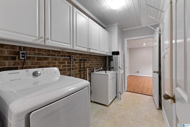 clothes washing area featuring cabinets, wood ceiling, brick wall, washer and dryer, and crown molding