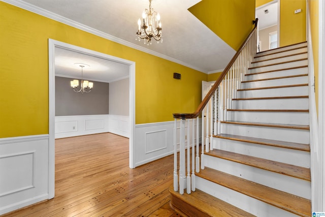 staircase featuring ornamental molding, a chandelier, and wood-type flooring