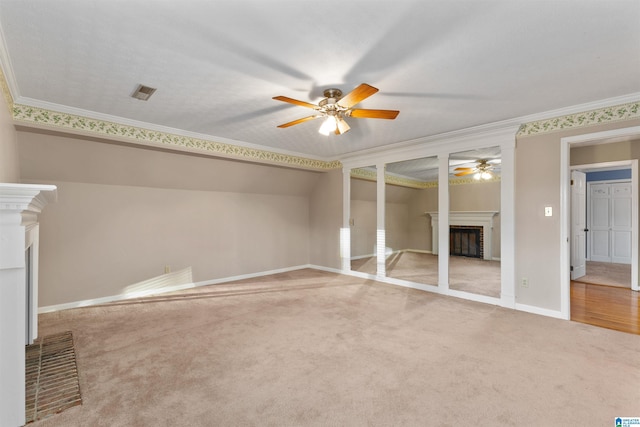 unfurnished bedroom featuring ceiling fan, crown molding, carpet floors, and a brick fireplace