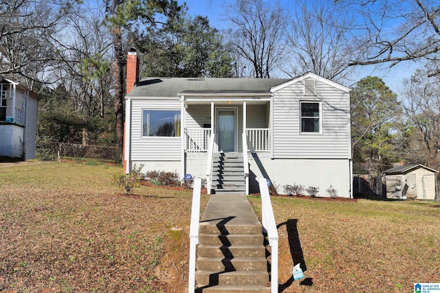 view of front of home featuring a storage unit and a front yard