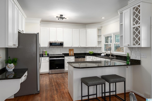 kitchen with a peninsula, a sink, white cabinets, appliances with stainless steel finishes, and open shelves