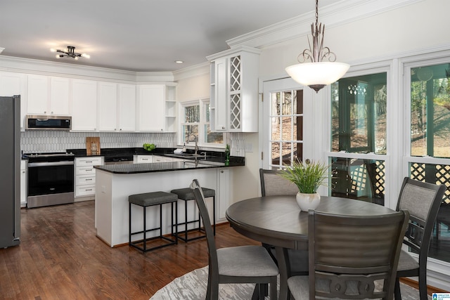 kitchen with stainless steel appliances, a sink, white cabinets, open shelves, and decorative light fixtures