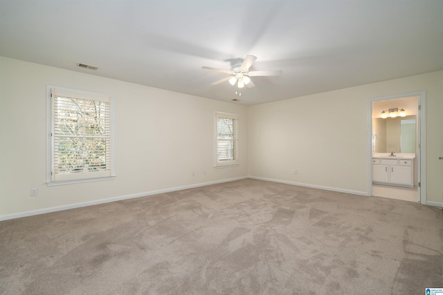 unfurnished bedroom with baseboards, visible vents, connected bathroom, light colored carpet, and a sink