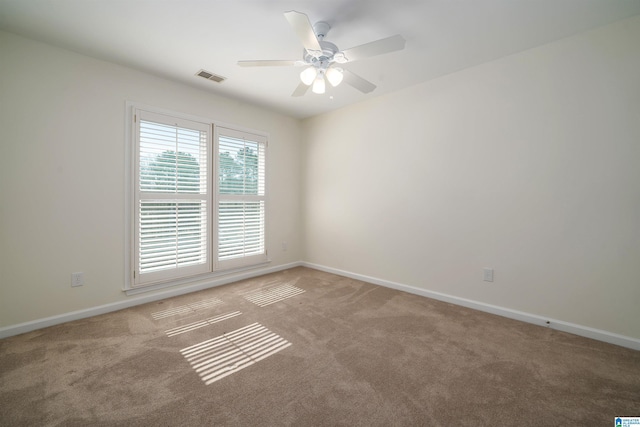 carpeted spare room with baseboards, visible vents, and a ceiling fan