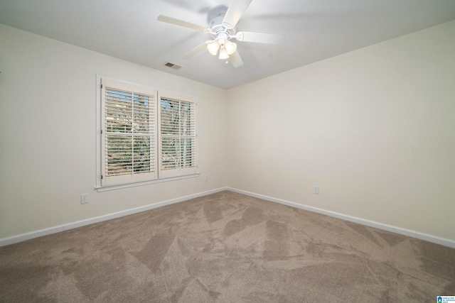 carpeted empty room featuring a ceiling fan, visible vents, and baseboards