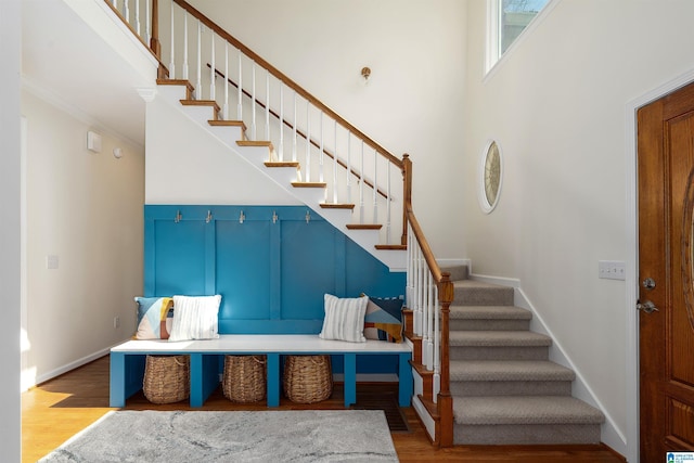 interior space with stairway, a towering ceiling, light wood-style flooring, and baseboards