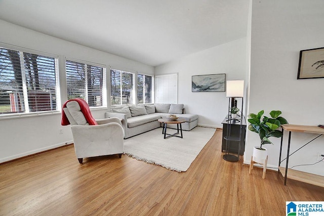 living room with light wood finished floors, baseboards, and vaulted ceiling