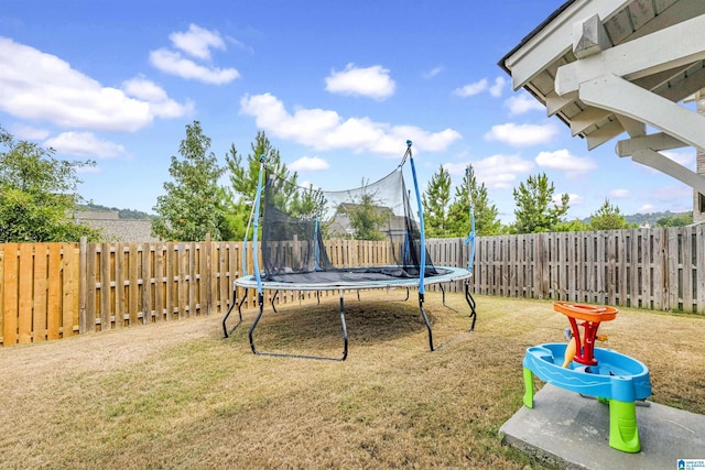 view of yard with a trampoline and a fenced backyard