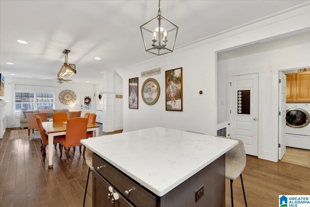 kitchen featuring dark brown cabinetry, light countertops, dark wood-style floors, washer / clothes dryer, and pendant lighting