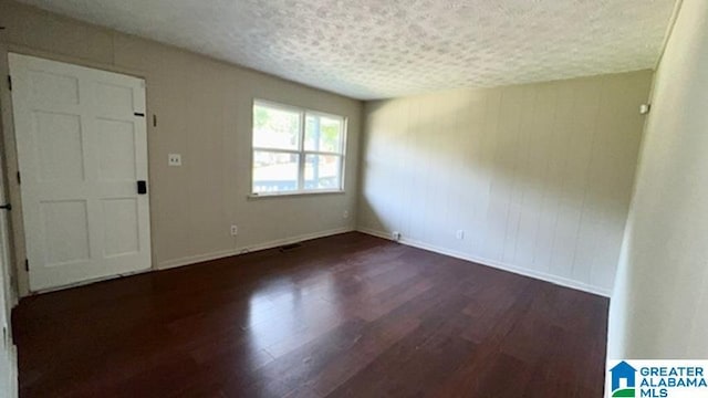 spare room with a textured ceiling and dark hardwood / wood-style floors