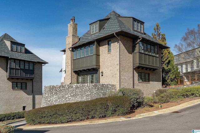 view of side of home featuring brick siding and a chimney