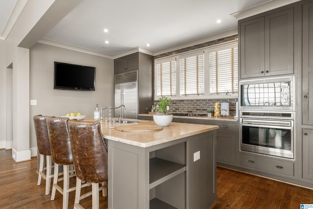 kitchen with built in appliances, gray cabinets, and a kitchen island