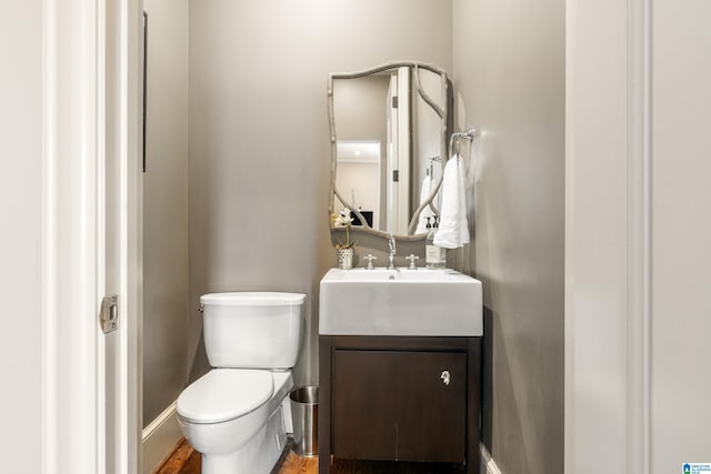 bathroom with toilet, vanity, and baseboards