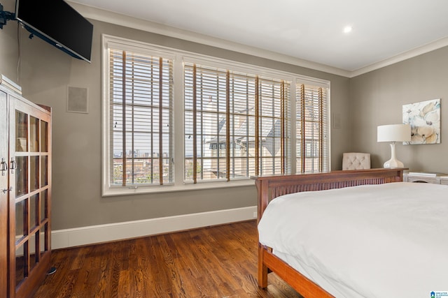 bedroom with dark wood-type flooring, ornamental molding, and baseboards