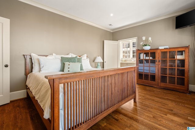 bedroom with baseboards, visible vents, crown molding, and wood finished floors