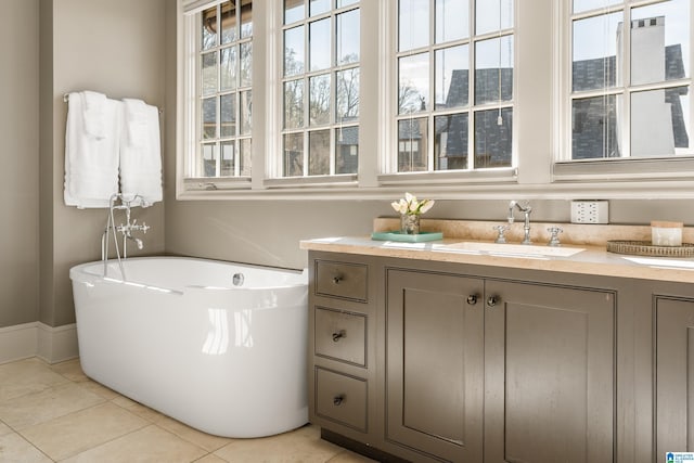 bathroom with tile patterned flooring, a freestanding tub, vanity, and baseboards