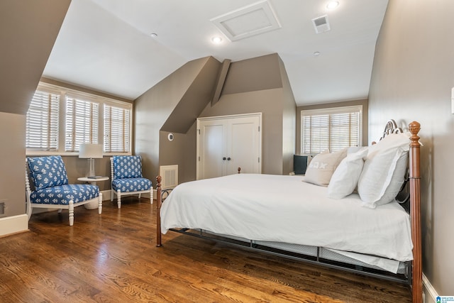 bedroom featuring lofted ceiling, wood finished floors, visible vents, baseboards, and attic access