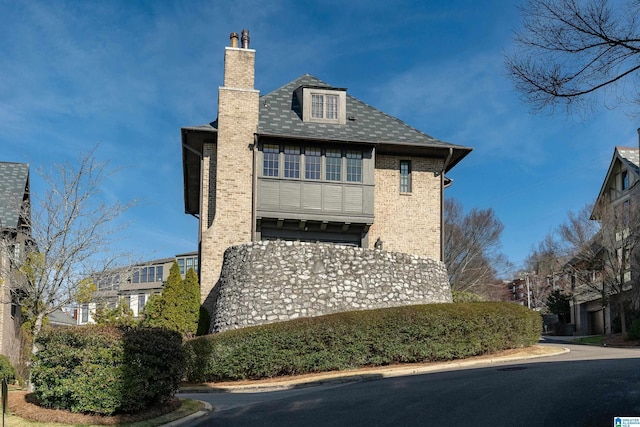 view of side of home with a chimney and brick siding