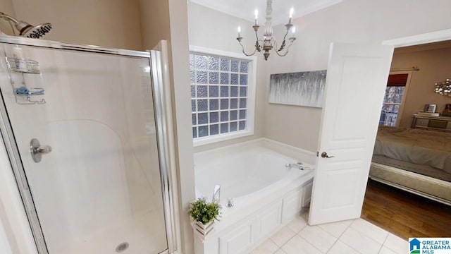 bathroom with an inviting chandelier, a garden tub, a shower stall, tile patterned flooring, and ensuite bathroom