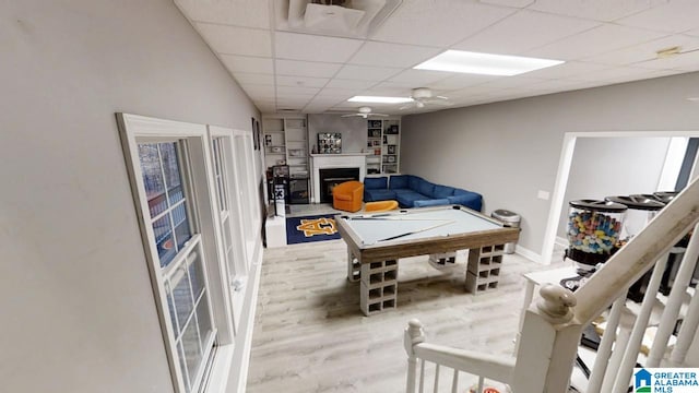 playroom featuring ceiling fan, billiards, a drop ceiling, wood finished floors, and a fireplace