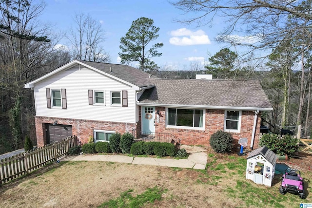 tri-level home featuring a shingled roof, brick siding, fence, and a chimney