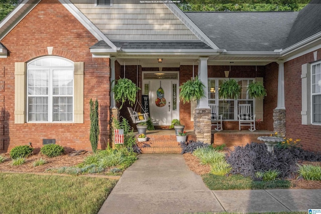 entrance to property with brick siding, crawl space, roof with shingles, and covered porch