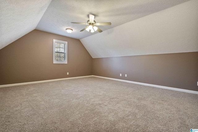 bonus room featuring carpet, baseboards, lofted ceiling, a textured ceiling, and ceiling fan