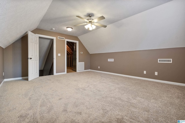 bonus room featuring visible vents, a textured ceiling, and light colored carpet