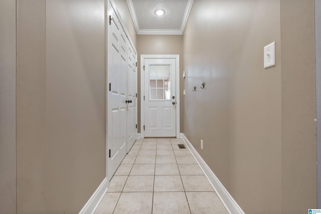 doorway to outside featuring a textured ceiling, ornamental molding, baseboards, and light tile patterned flooring