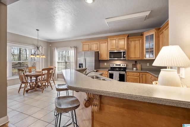 kitchen with glass insert cabinets, a sink, light countertops, light tile patterned floors, and appliances with stainless steel finishes