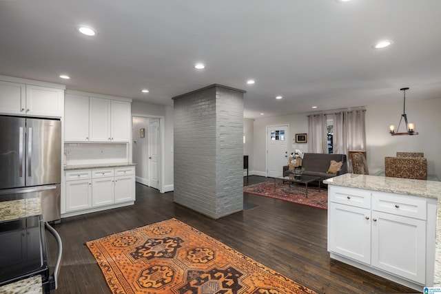 kitchen with hanging light fixtures, freestanding refrigerator, open floor plan, white cabinetry, and light stone countertops