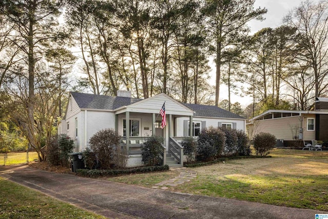 view of front facade featuring roof with shingles, a chimney, and a front yard