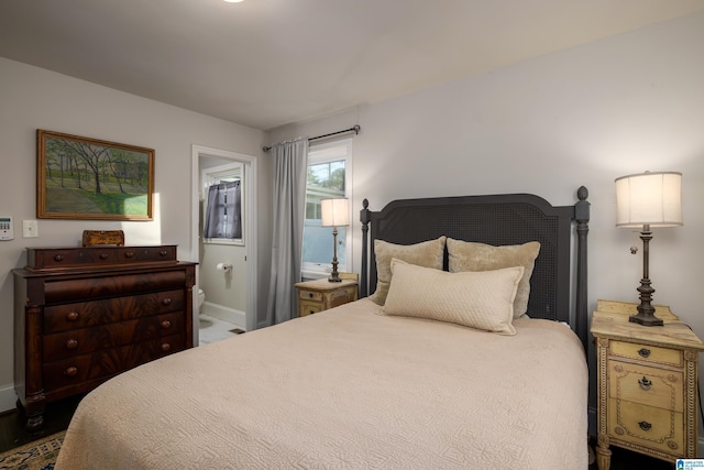 bedroom featuring ensuite bath and baseboards