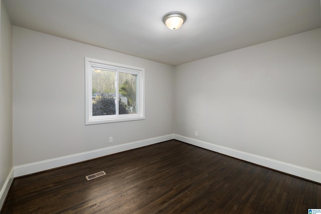 unfurnished room featuring baseboards, visible vents, and dark wood-type flooring