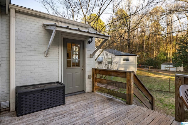 wooden deck with a shed, a lawn, an outdoor structure, and fence