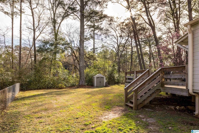 view of yard featuring an outbuilding, a storage unit, fence, a deck, and stairs